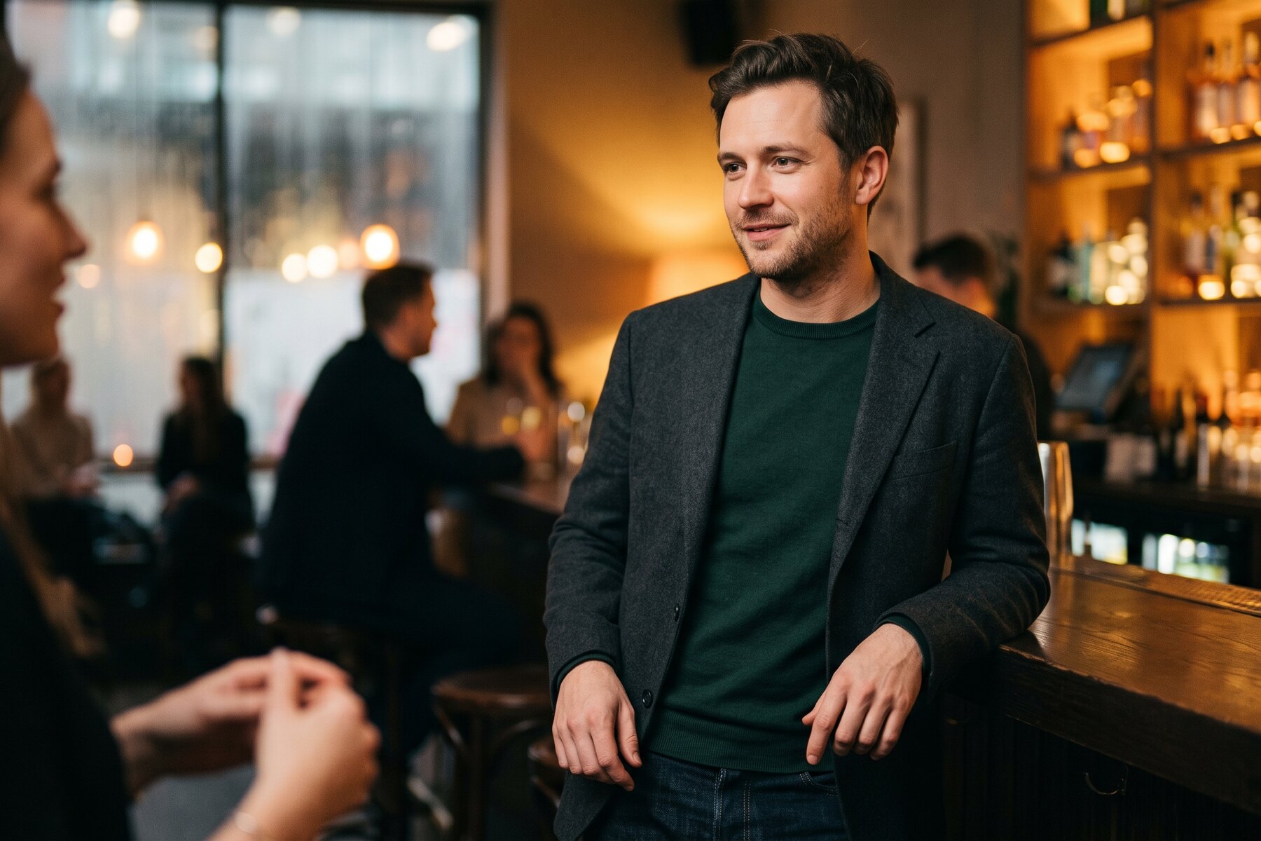 Man standing relaxed against a bar, mid-conversation